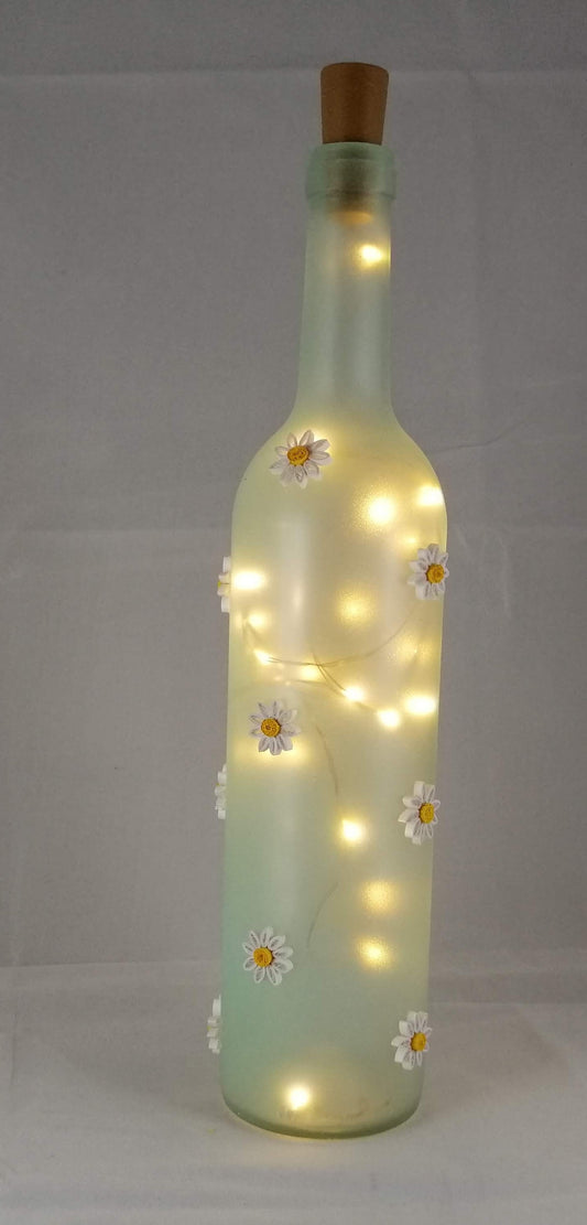 Glass bottle with daisies and lights