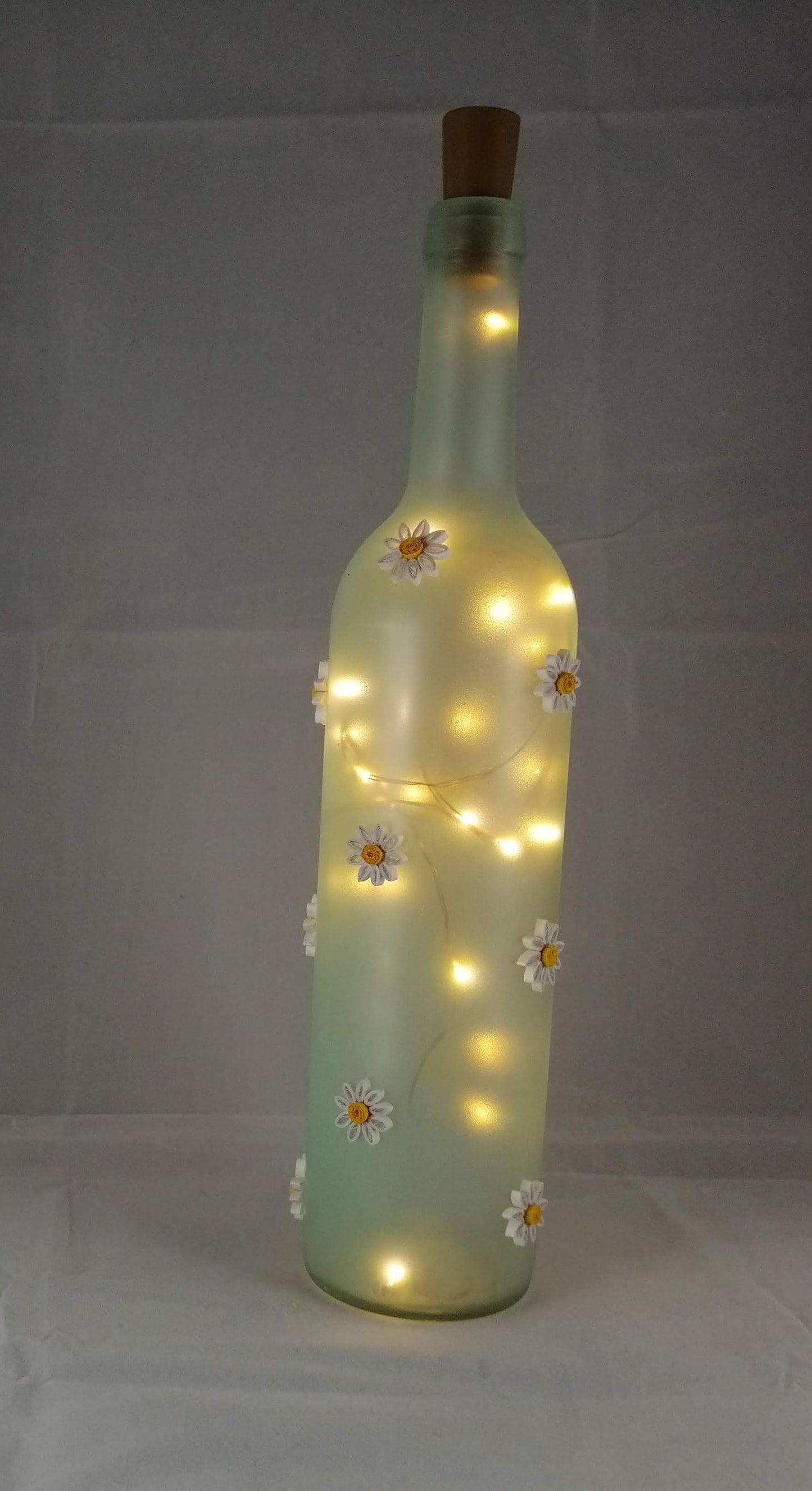 Glass bottle with daisies and lights